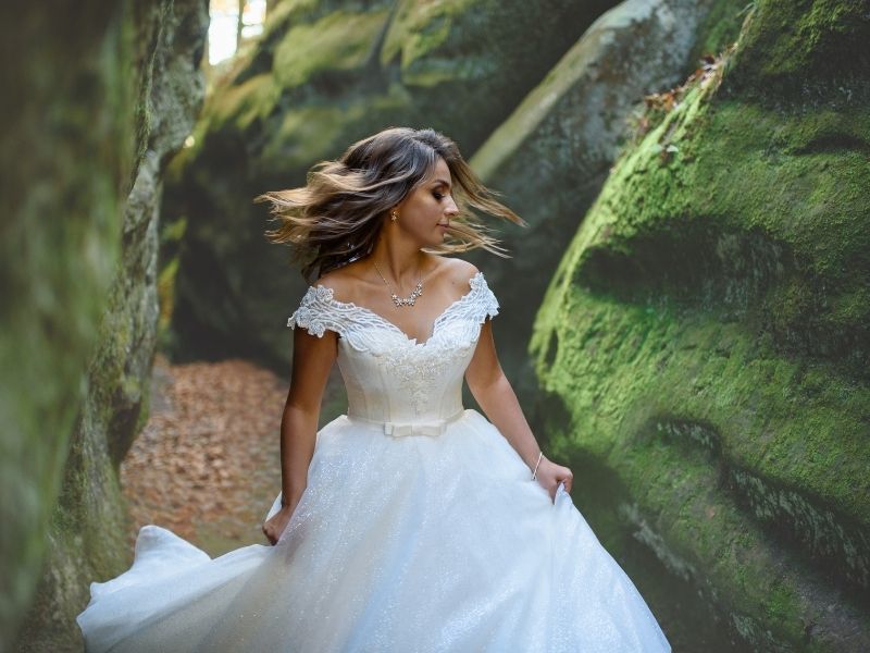 A bride spins in her gown in front of moss covered rocks