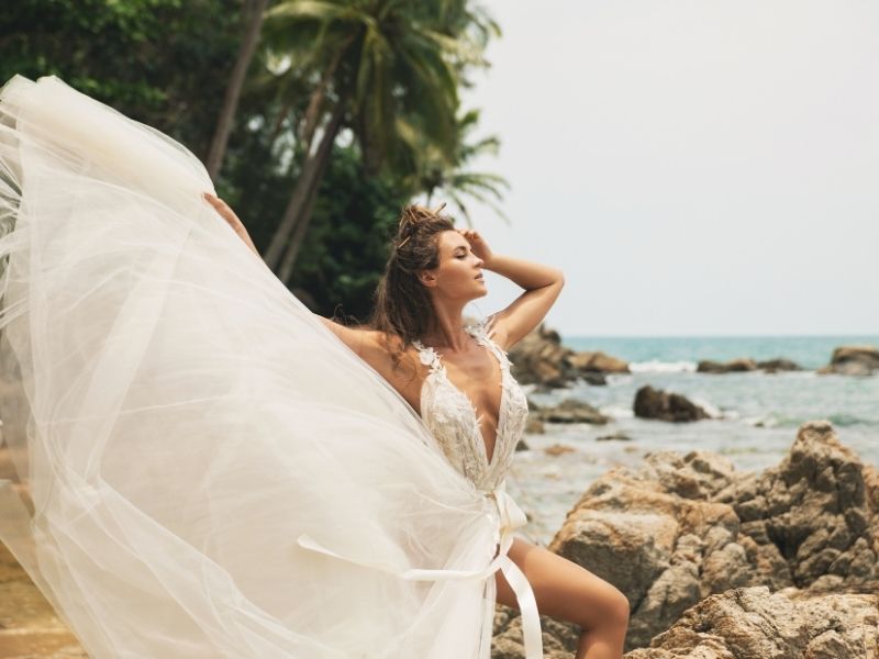 A bride models in her gown at a tropical beach.